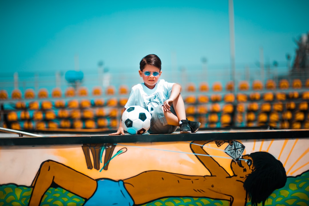 boy sitting on graffiti wall beside soccer ball