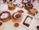 An assortment of dim sum dishes is arranged on a table. Wooden steamers hold items like buns and dumplings, while small plates display various dishes including chicken feet and rice noodles in sauce. A white teapot and cups filled with tea are also present, alongside dipping sauces.