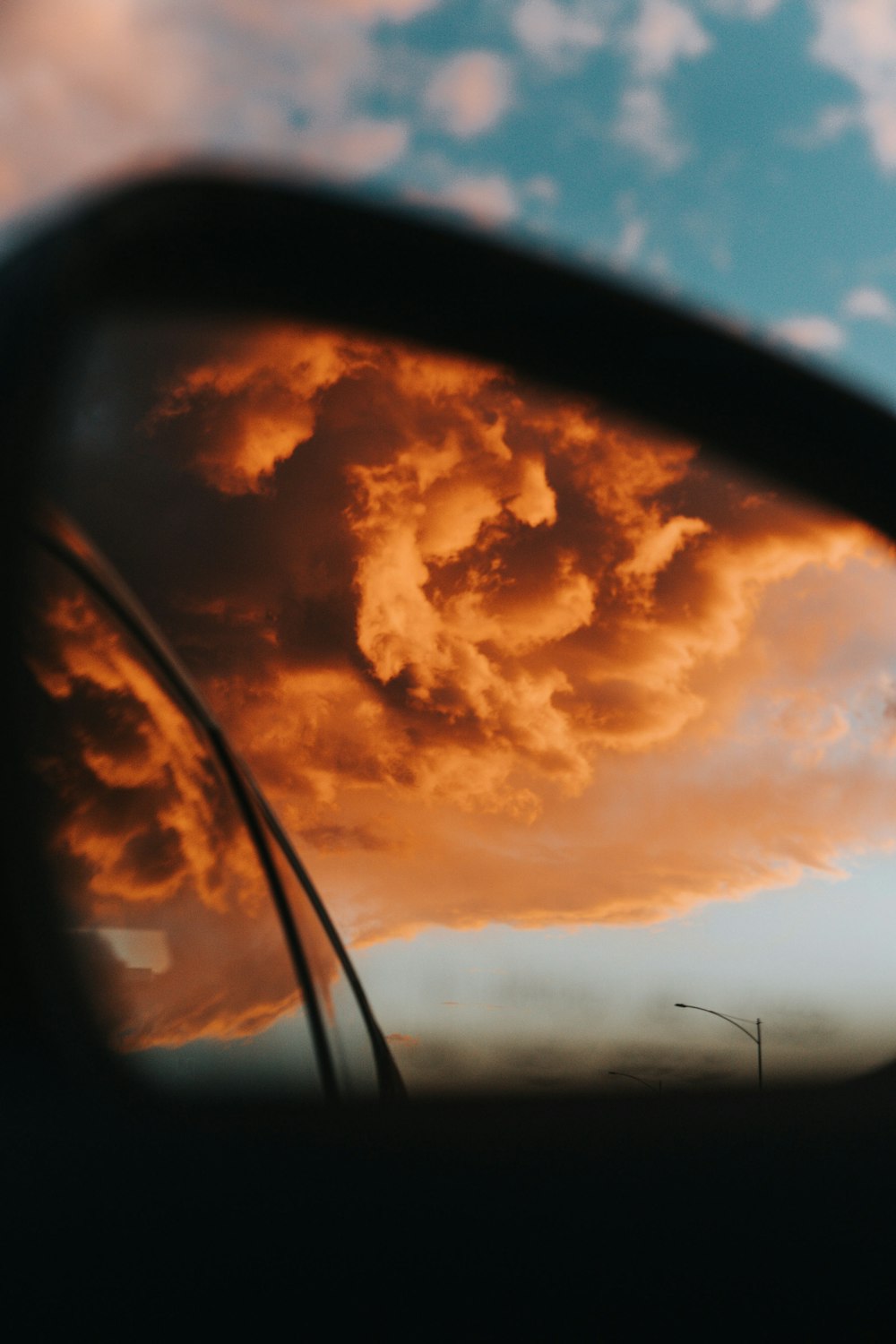 orange clouds viewed from vehicle side mirror
