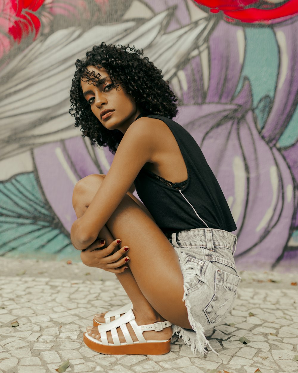 woman sitting beside concrete wall