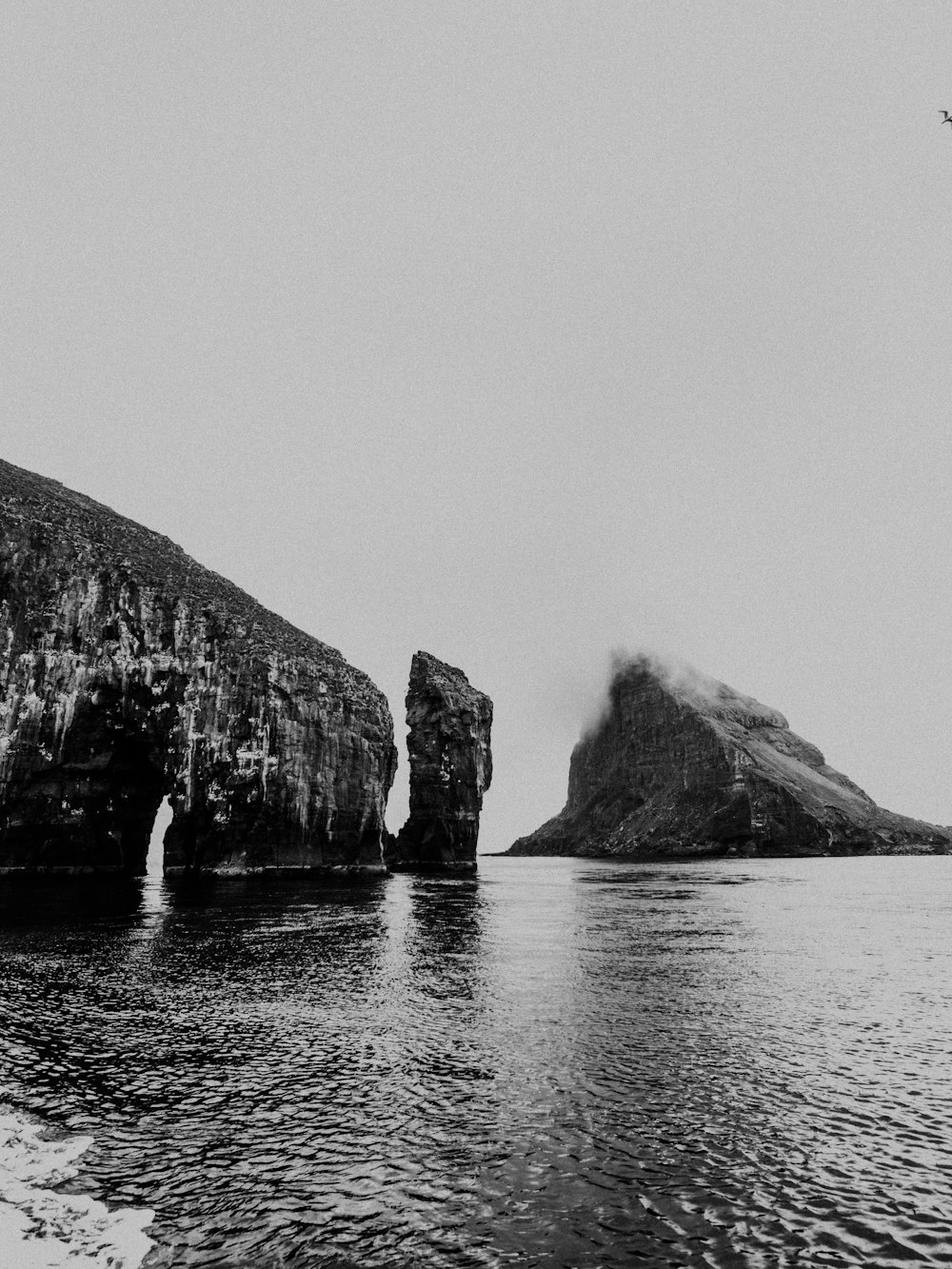 cliff by the body of water in monochrome