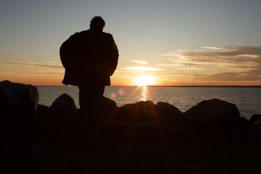 silhouette of person in front of body of water during daytime