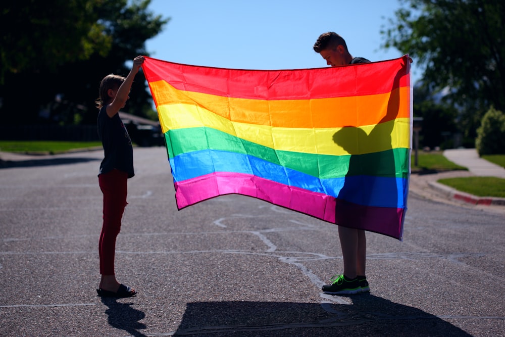 man and girl holding rainbow flag