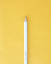 A white pencil with the words 'YOU GOT THIS' engraved on it stands upright against a bright yellow background. The pencil's tip is sharpened and points upwards.