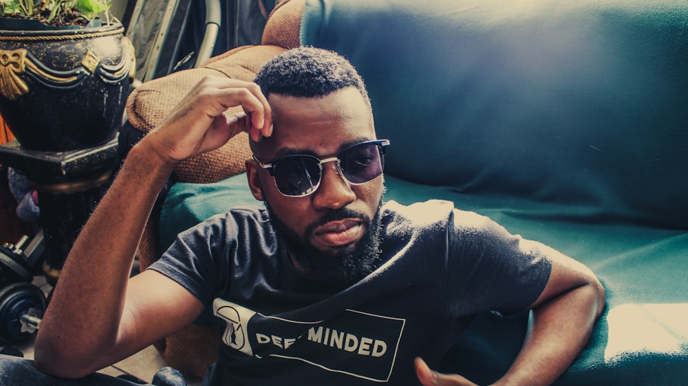 man wearing sunglasses leaning on green sofa during daytime