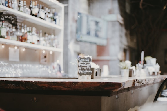 A cozy bar counter with colorful drinks and snacks served on wooden trays.