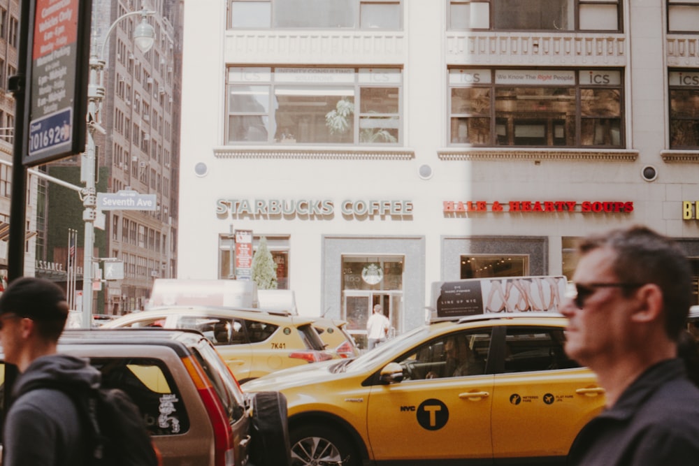 man wearing sunglasses walking passes by yellow vehicle during daytime