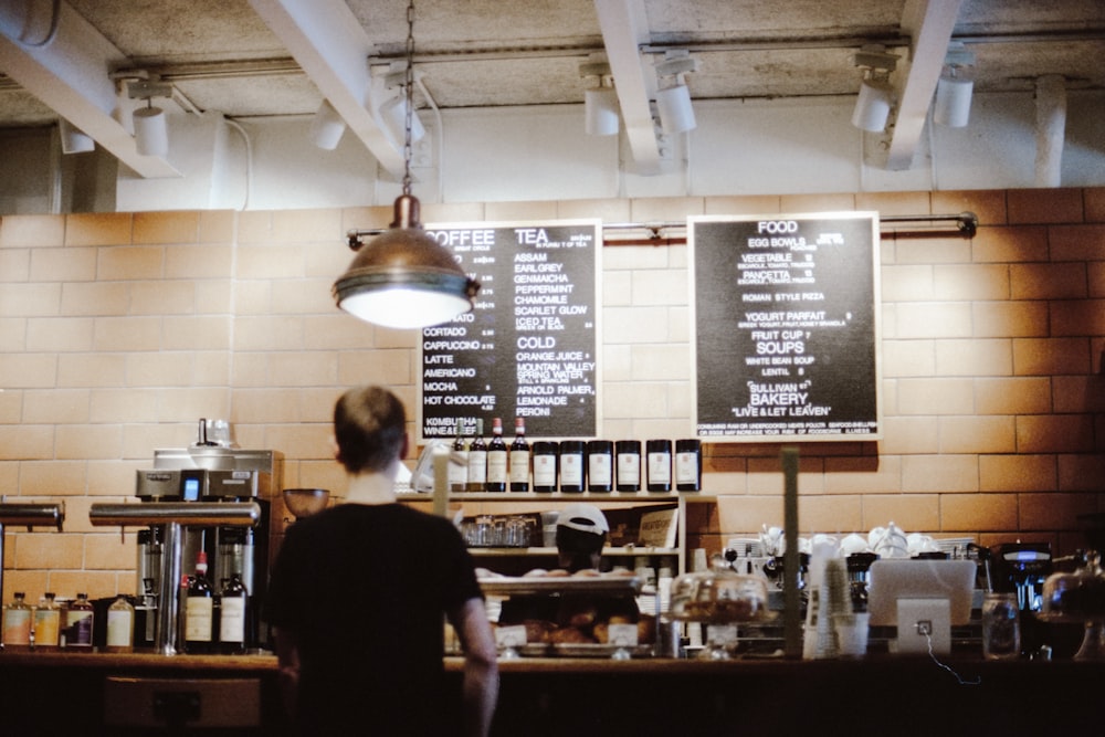 woman in black shirt standing in front of cafe menu