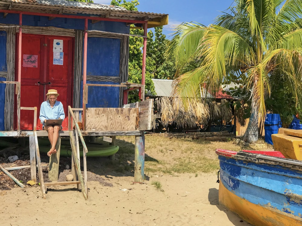 person sitting in-front of blue and red shed during daytime