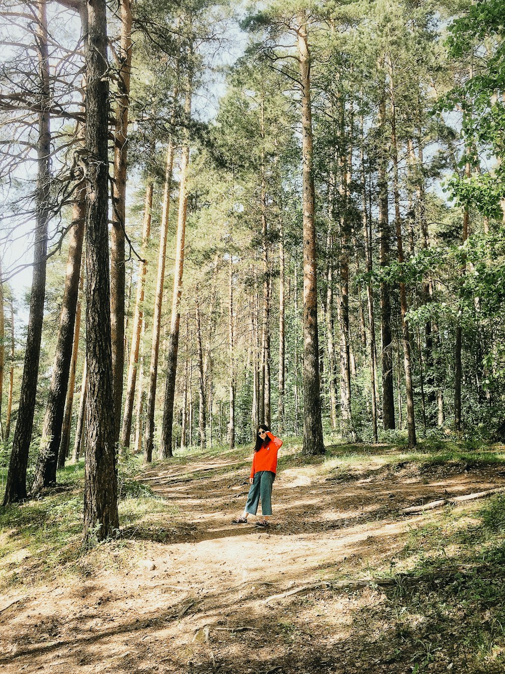 woman wearing orange jacket standing in the middle of forest