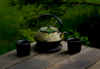 A peaceful corner with a handmade teapot and cup set, surrounded by plants.