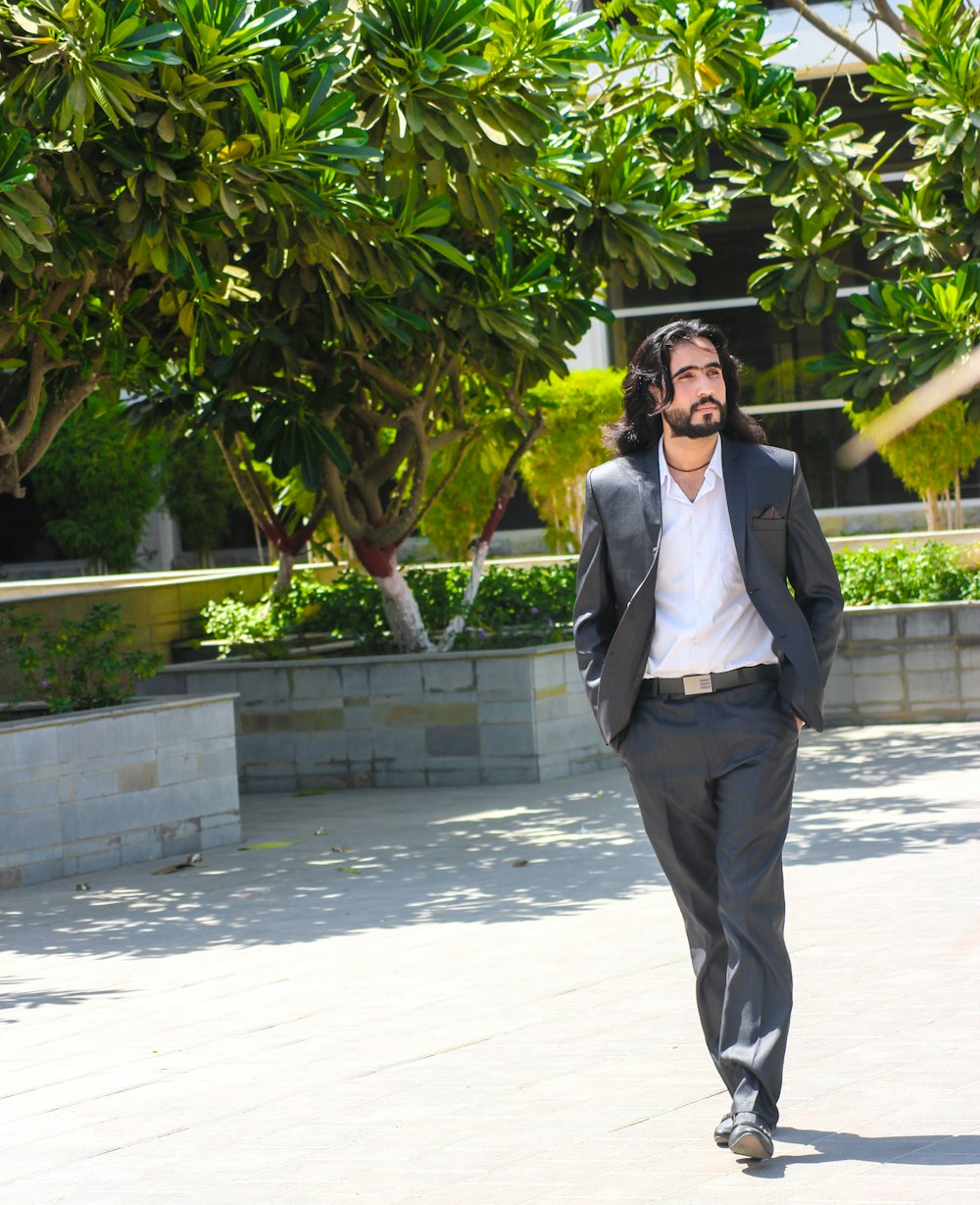 man in black suit jacket walking near trees