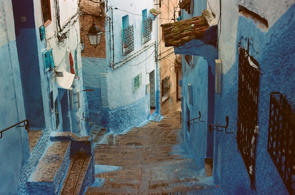 a narrow alleyway with blue walls and a wooden bench