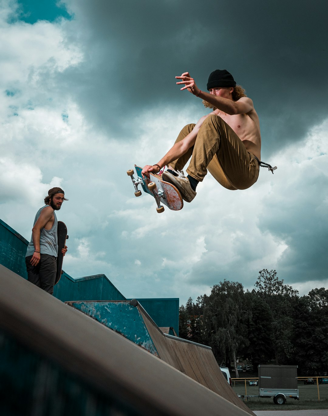 man in bonnet and brown pants jumping with skateboard