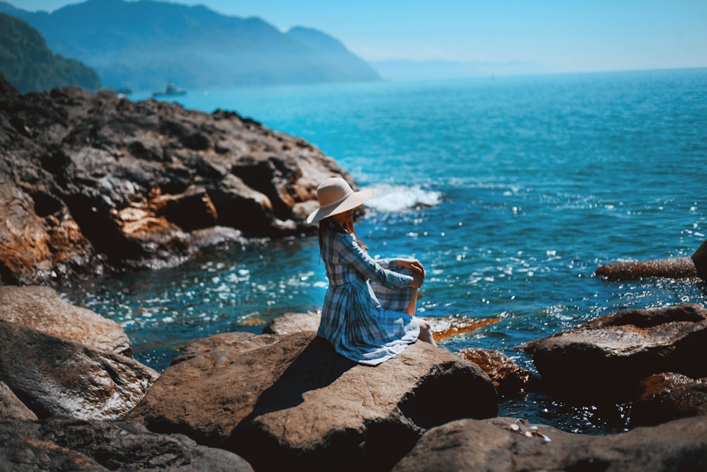 Mujer sentada en rocas cerca del cuerpo de agua