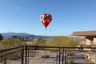 red, green, and blue hot air balloon flying near body of water during daytime