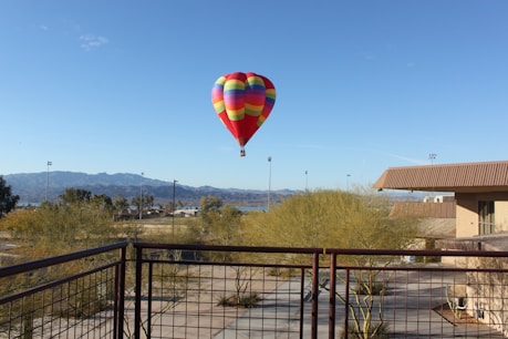 red, green, and blue hot air balloon flying near body of water during daytime