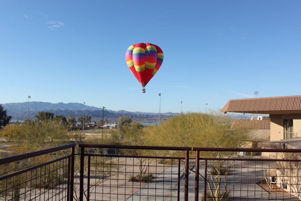 red, green, and blue hot air balloon flying near body of water during daytime
