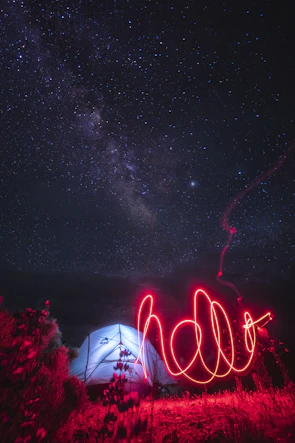 red light streak near lighted tent under starry night sky