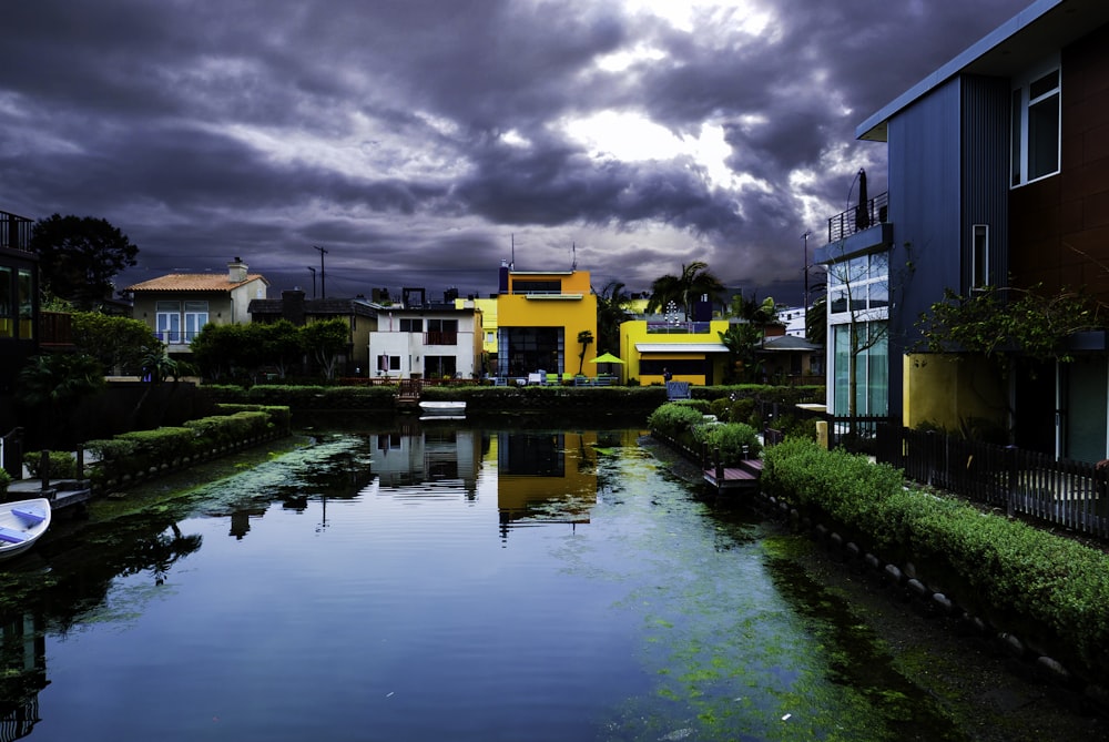 buildings near body of water under cloudy sky during daytime