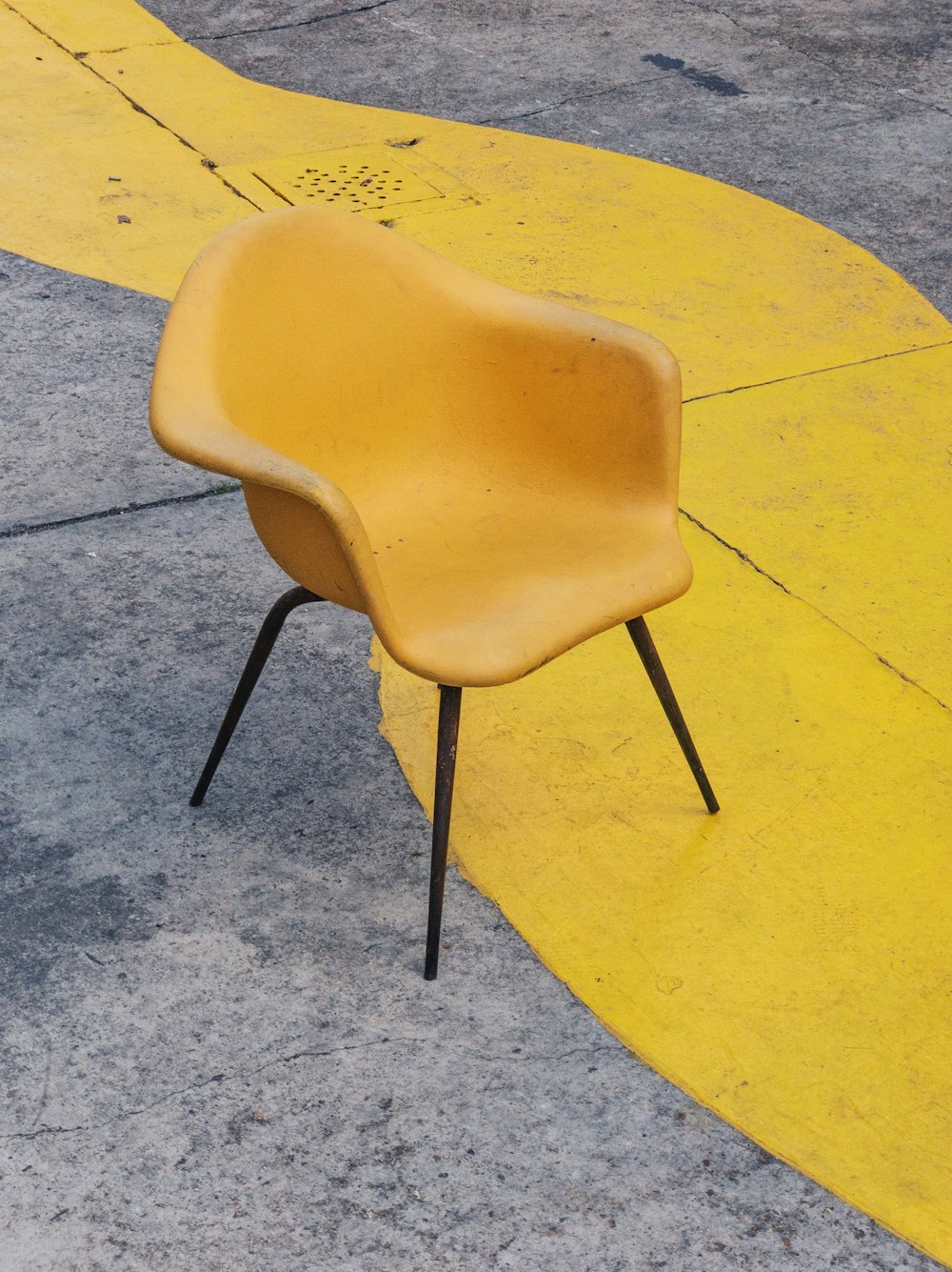 yellow plastic chair on yellow and gray concrete surface