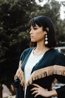 Street-style shot of a young woman showcasing bold statement earrings against an urban backdrop.