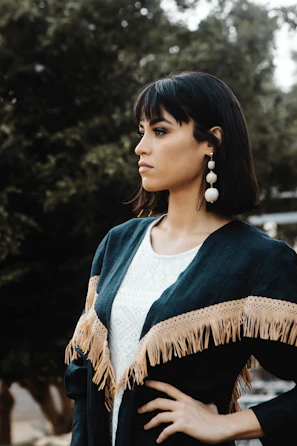 Street-style shot of a young woman showcasing bold statement earrings against an urban backdrop.