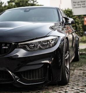 A close-up of a sleek black car with a 'Sold' sign on the windshield.