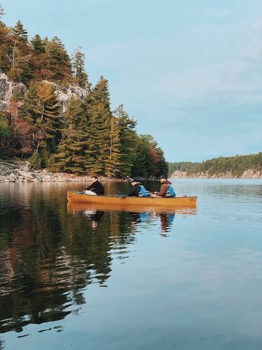 three people riding canoe on lake in Killarney Canada