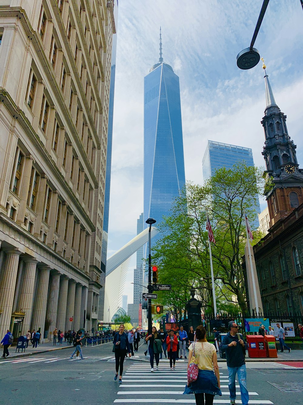 people crossing across gray tower building