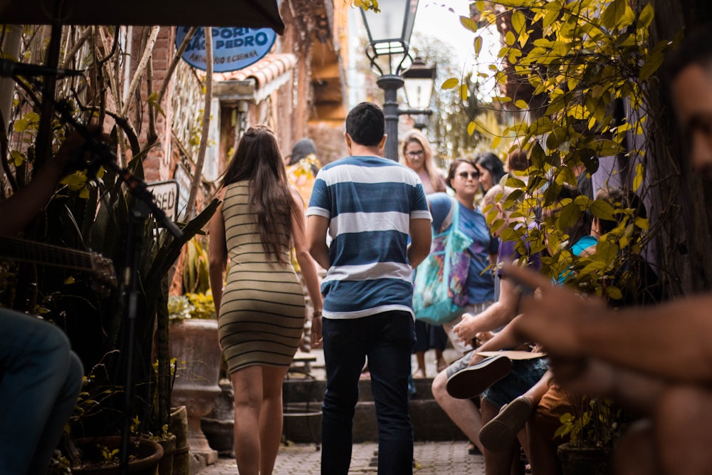 man wearing blue and white stripe shirt besides woman wearing brown and black stripe body con dress