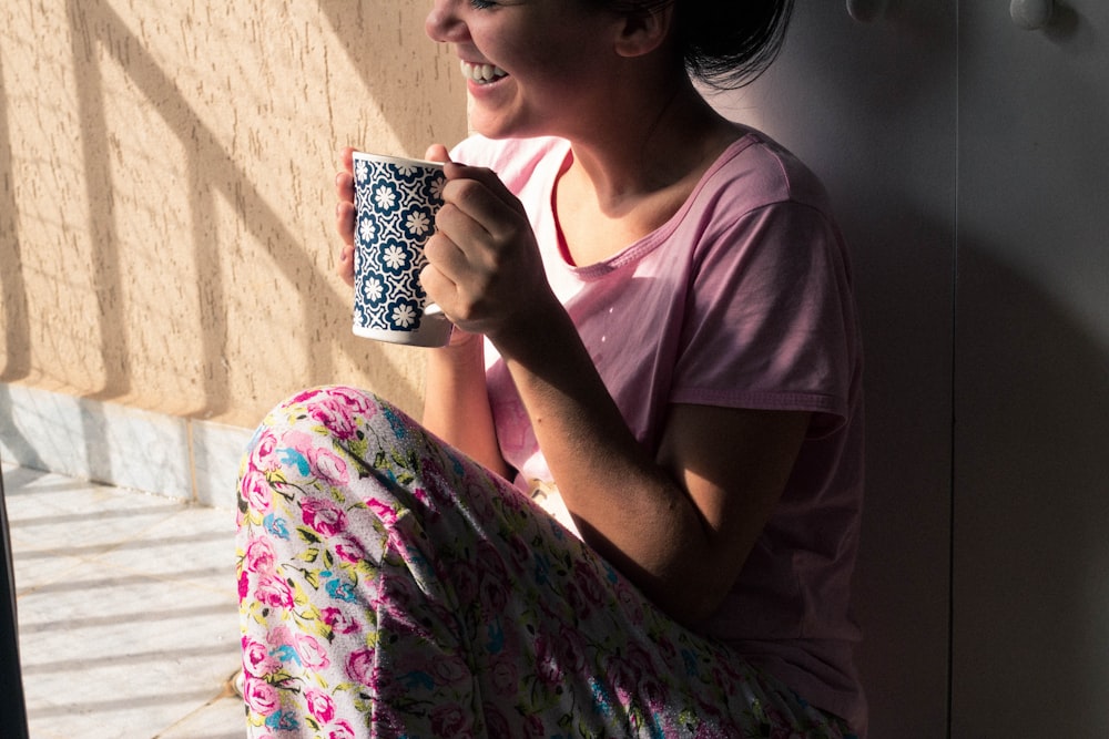 woman wearing pink top while holding mug