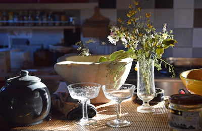 A cozy kitchen scene featuring a set of colorful stoneware bowls stacked beside fresh herbs and a steaming teapot.