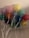 A cluster of colorful balloons with white strings attached, floating indoors against a light-colored ceiling.