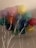 A cluster of colorful balloons with white strings attached, floating indoors against a light-colored ceiling.