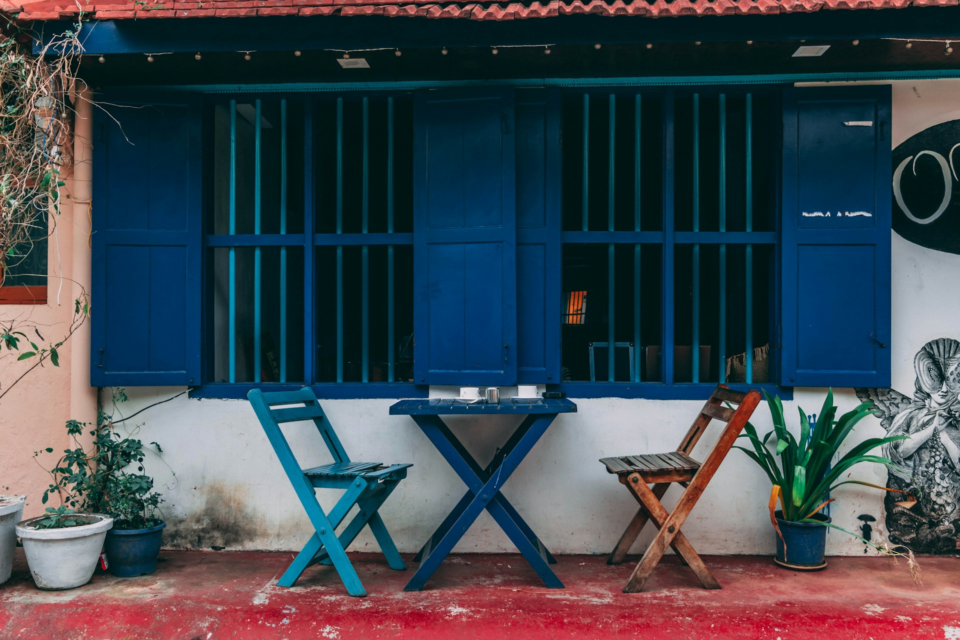 A vibrant outdoor patio scene showcasing colorful chairs around a rustic wooden table.