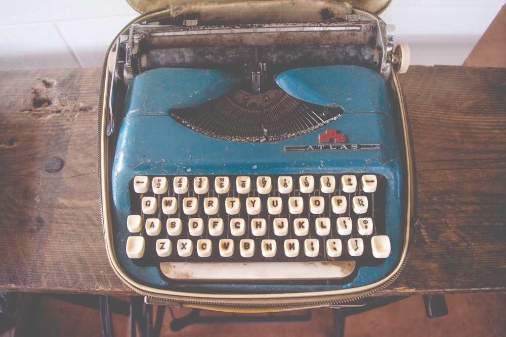 blue and white typewriter on brown wooden consoel