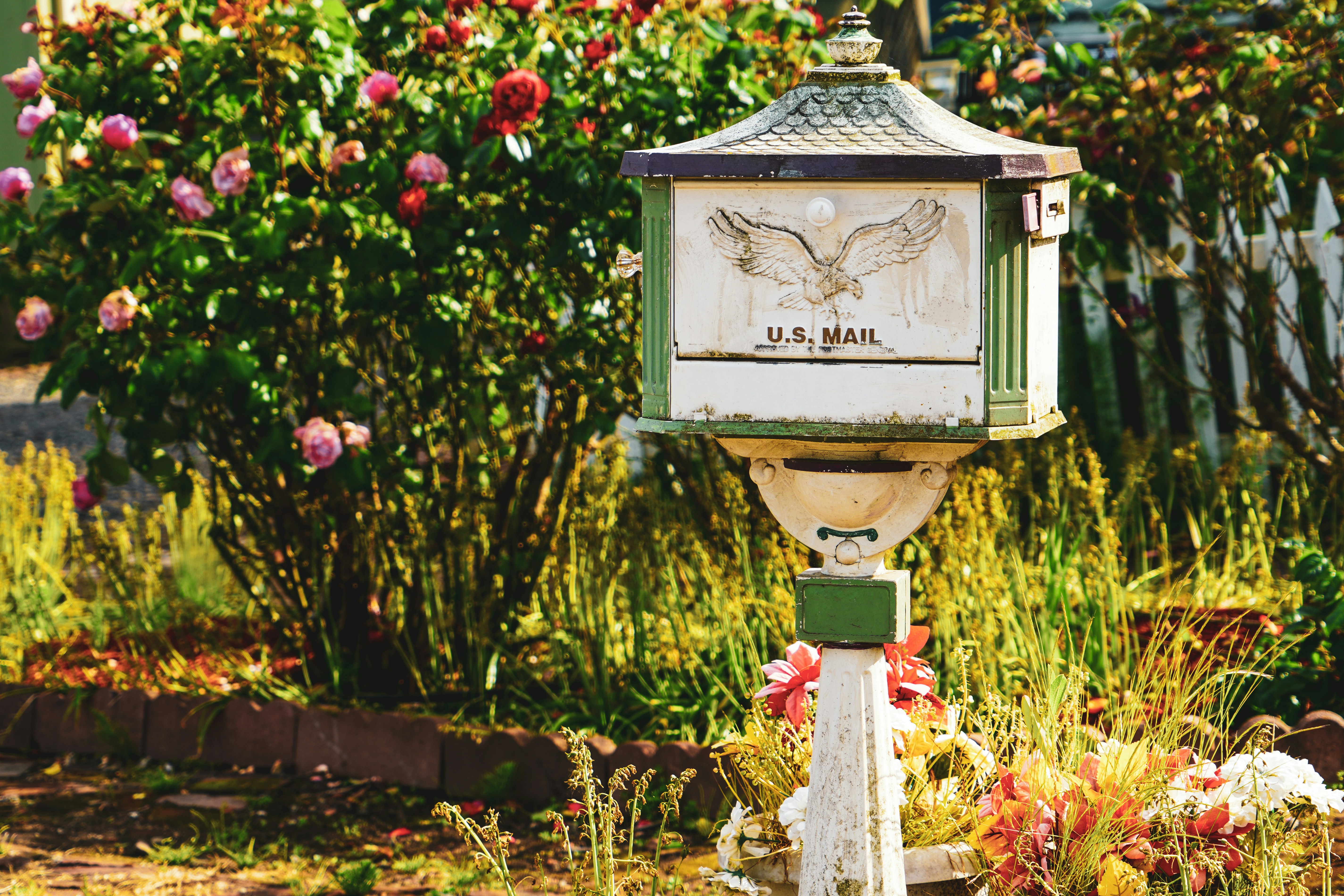 white and green US Mail pedestal mailbox near flowers
