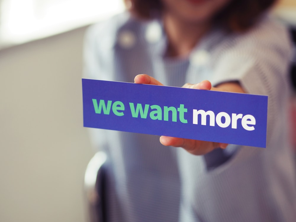 woman holding we want more sign