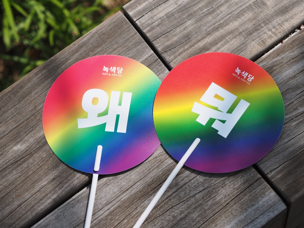 two round multicolored decors with sticks on wooden surface