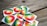 A collection of stickers and buttons featuring a rainbow gradient background with white text in a non-Latin script placed on a wooden surface.