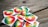 A collection of stickers and buttons featuring a rainbow gradient background with white text in a non-Latin script placed on a wooden surface.
