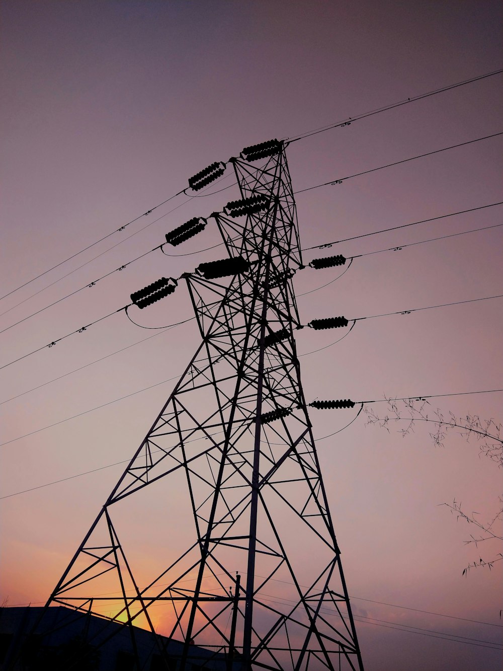 grey power transmission tower under purple sunset sky
