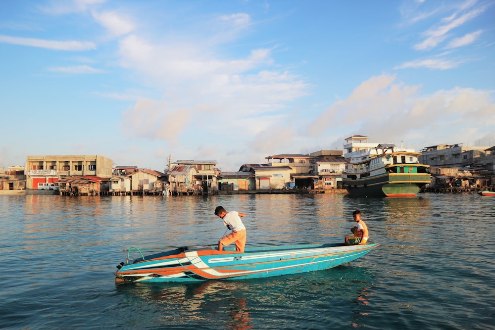 two person rowing boat near city