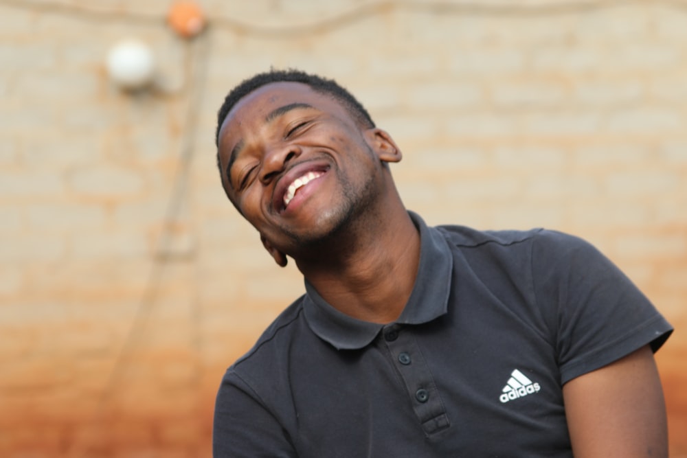 smiling man in black adidas polo shirt