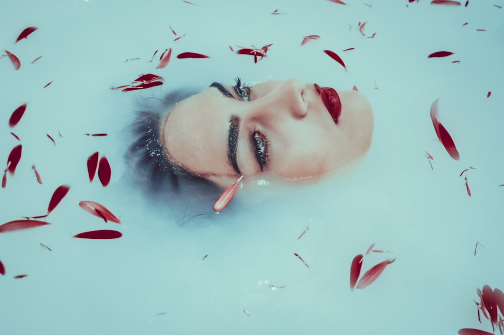 woman's face in water surrounded with brown leaves