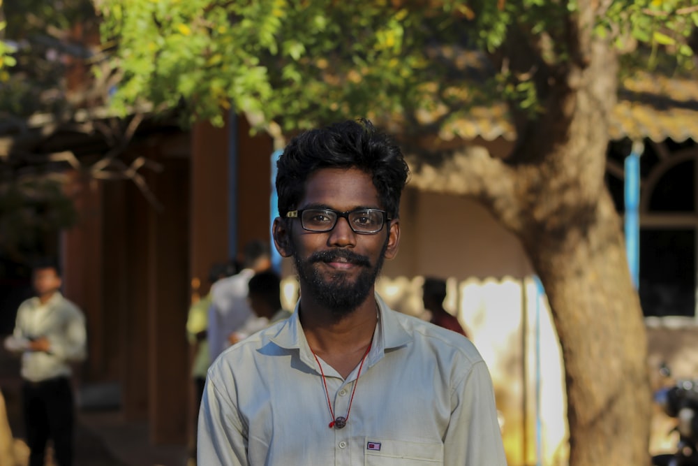 selective focus photography of smiling man wearing gray collared shirt and eyeglasses