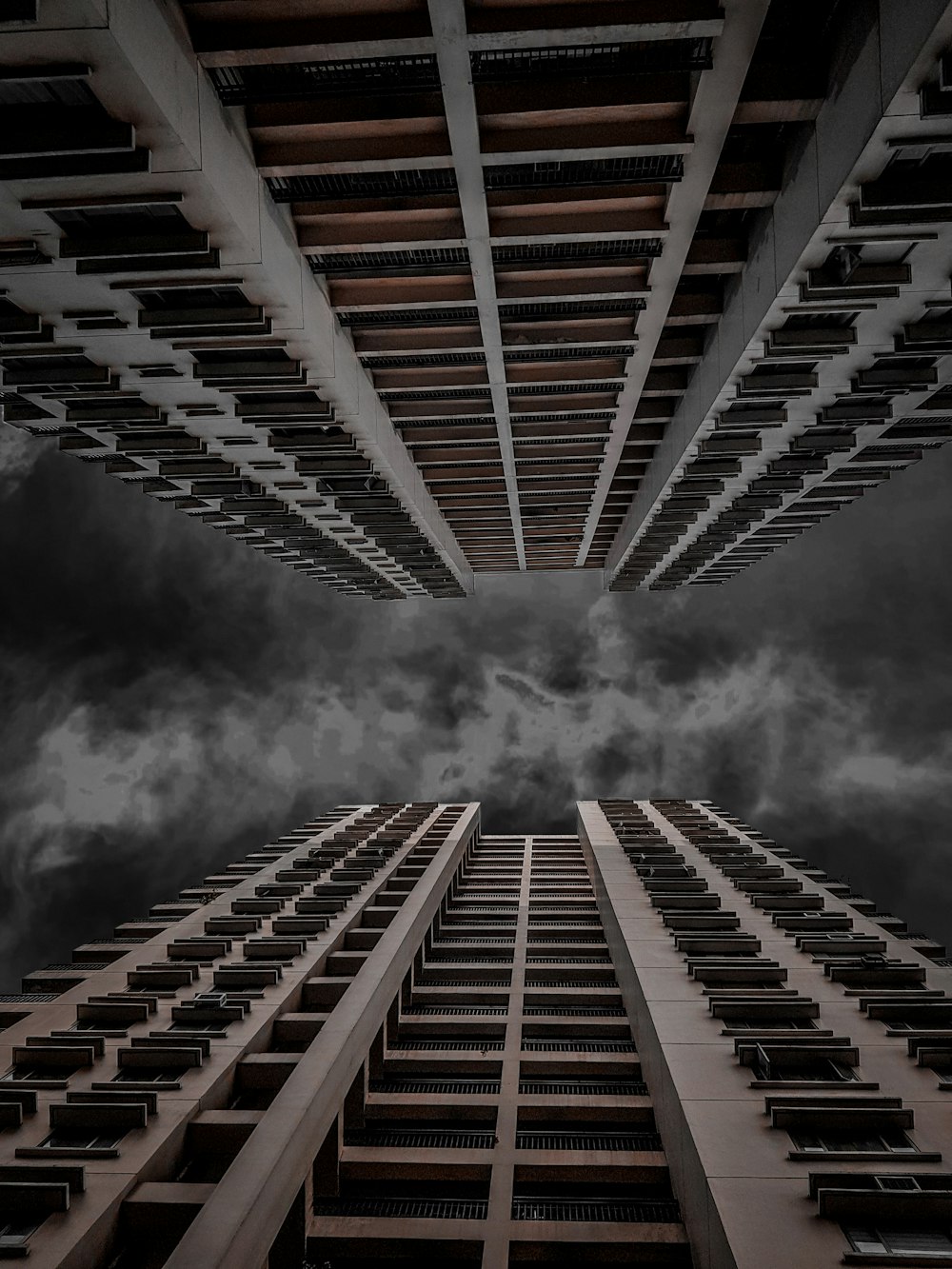 흐린 하늘 아래 두 개의 고층 건물의 로우 앵글 사진