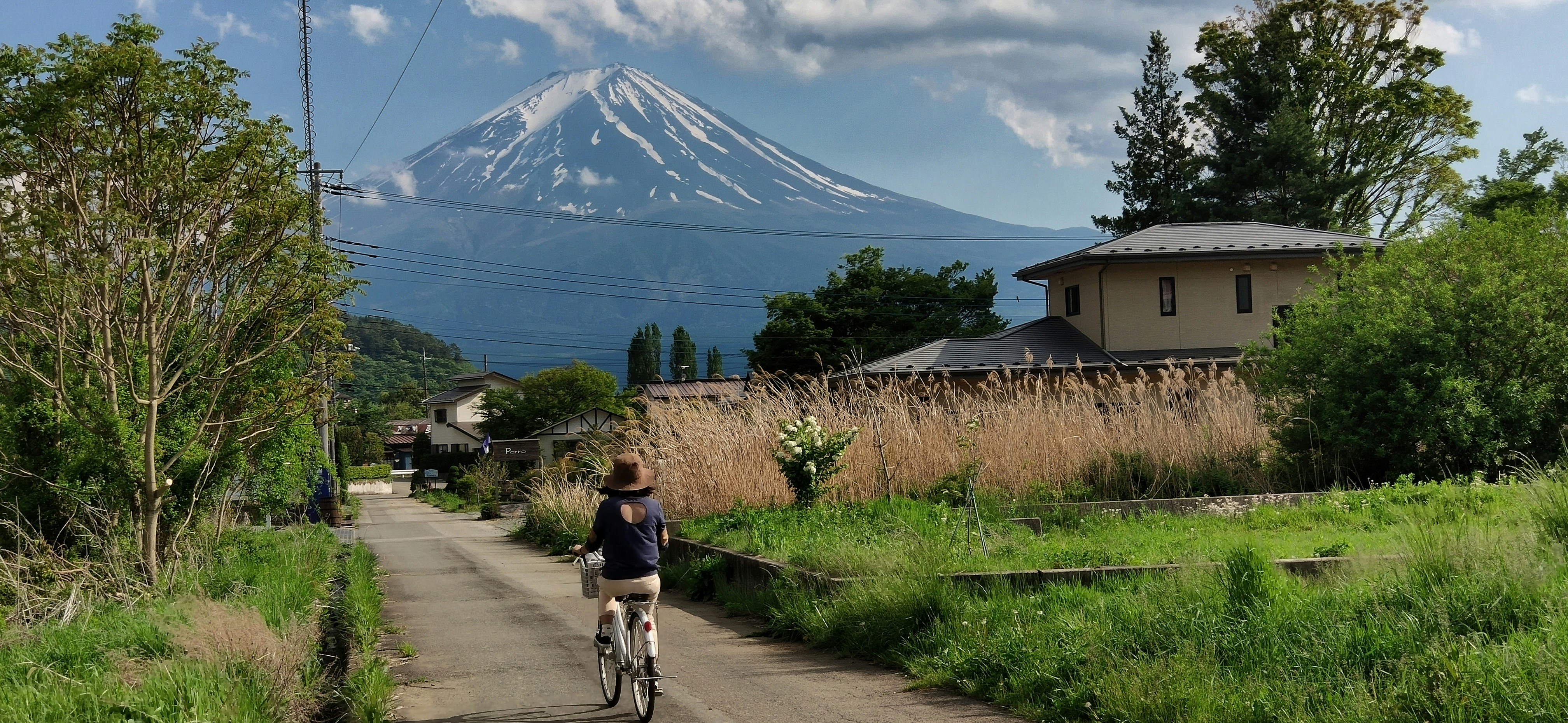 woman riding bike passing by near house during daytime