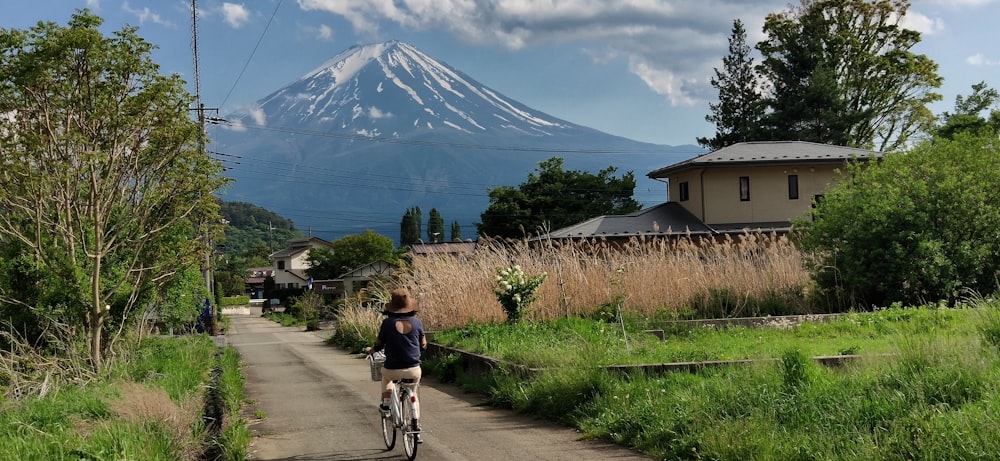 mujer montando en bicicleta pasando cerca de casa durante el día